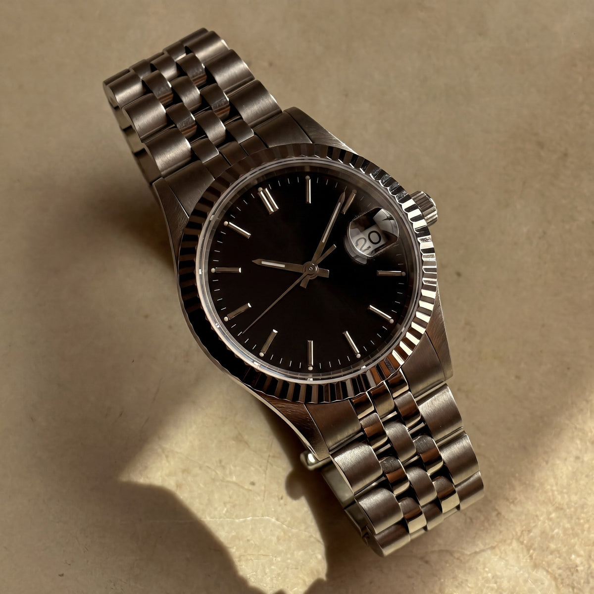 Trente-Neuf Noir — vue de face, cadran noir soleillé, lunette cannelée acier et bracelet cinq rangs — Maison Noirmont