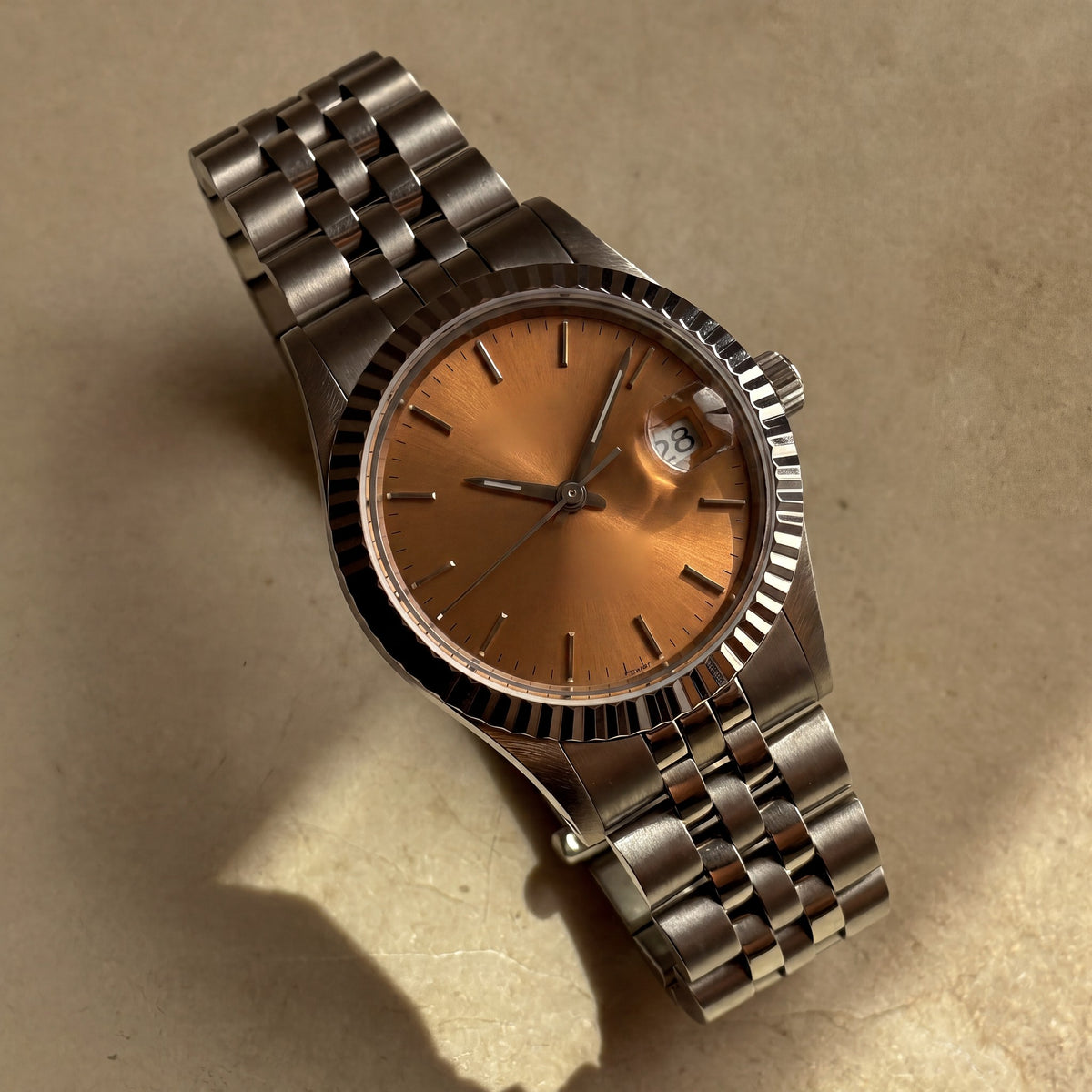 Trente-Neuf — cadran orange soleillé, index bâtons appliqués, lunette cannelée acier et bracelet cinq rangs — Maison Noirmont