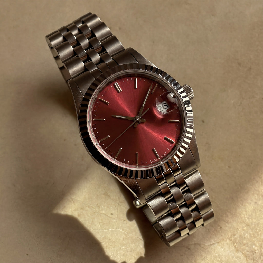 Trente-Neuf — cadran rouge soleillé, index bâtons appliqués, lunette cannelée acier et bracelet cinq rangs — Maison Noirmont