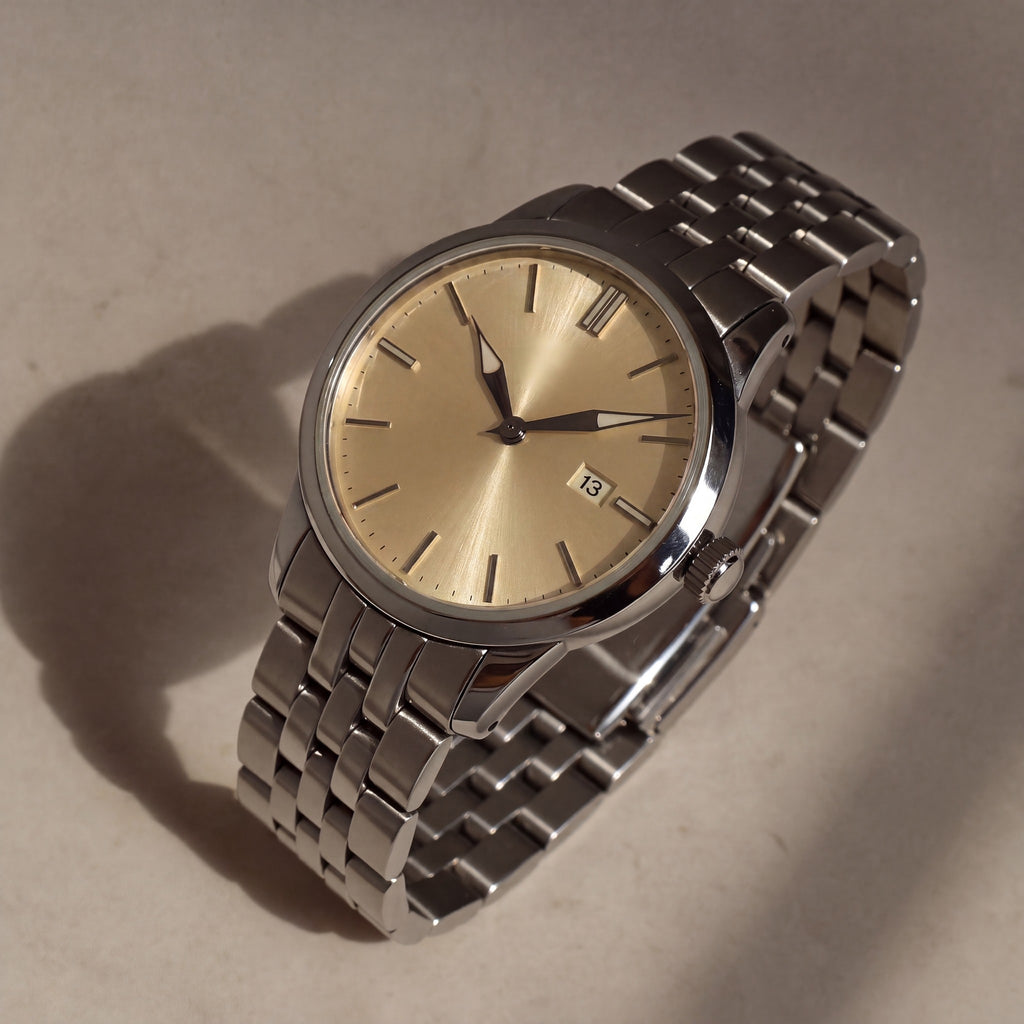 Trente-Six Doré — vue de face, cadran champagne soleillé, index bâtons appliqués et bracelet cinq rangs acier — Maison Noirmont