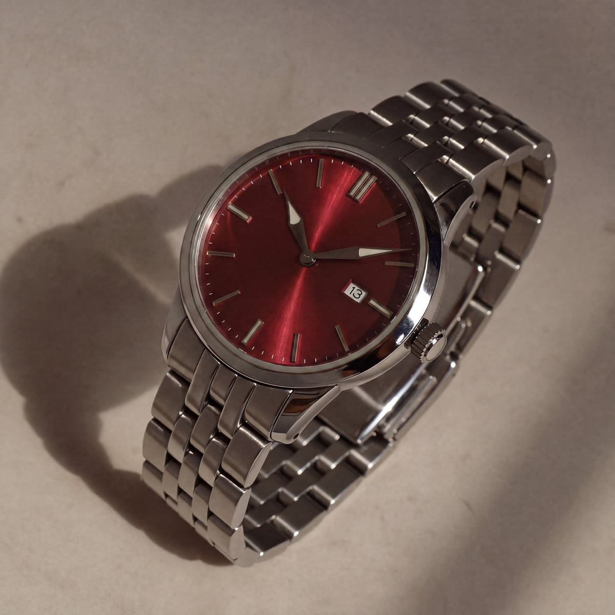 Trente-Six Rouge — vue de face, cadran rouge soleillé, index bâtons appliqués et bracelet cinq rangs acier — Maison Noirmont