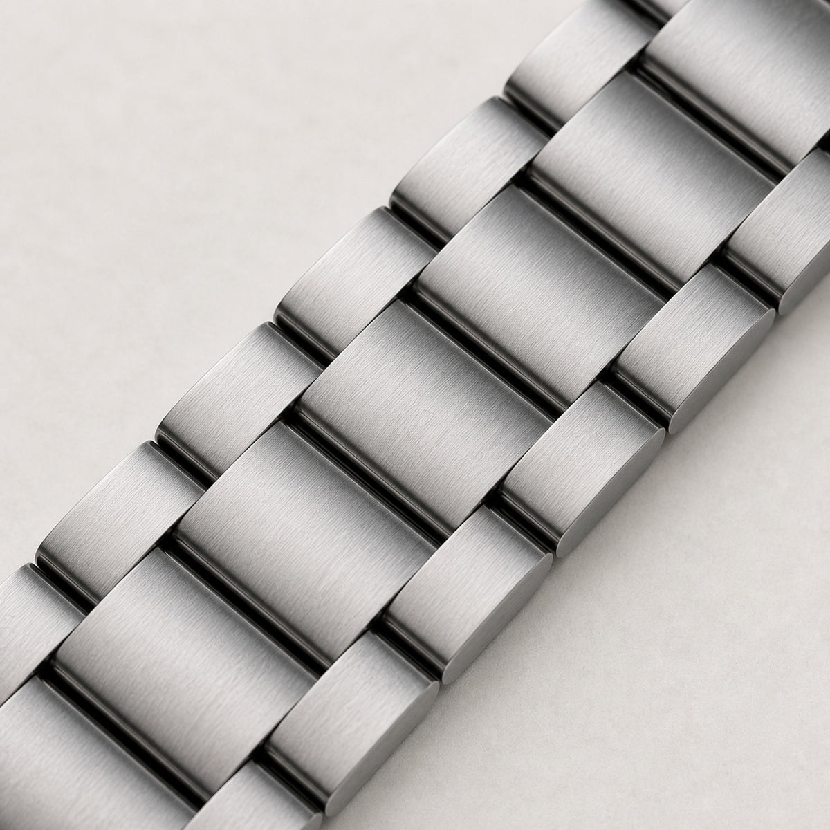 Contre-la-montre Rose poudré — macro du bracelet acier trois maillons et de son grain brossé — Maison Noirmont