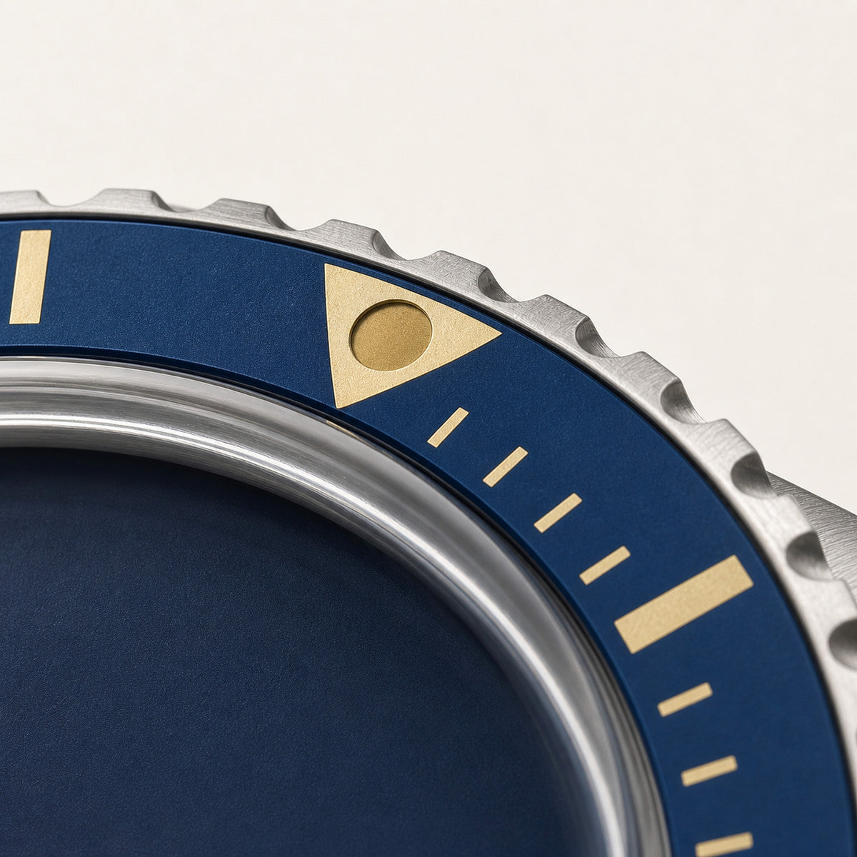 Héritage Bleu — macro oblique de la lunette bleue, de son repère triangulaire doré et de sa denture acier — Maison Noirmont