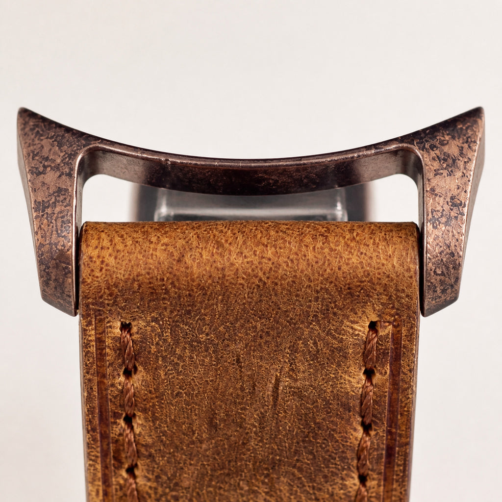 Éclaireur Bronze — macro de la jonction entre les cornes bronze à finition vieillie mouchetée et le bracelet cuir caramel texturé à surpiqûres brunes — Maison Noirmont