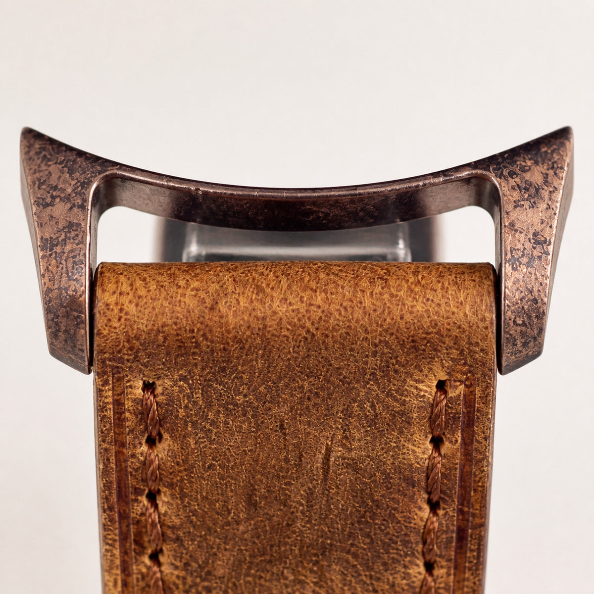 Éclaireur Bronze — macro de la jonction entre les cornes bronze à finition vieillie mouchetée et le bracelet cuir caramel texturé à surpiqûres brunes — Maison Noirmont