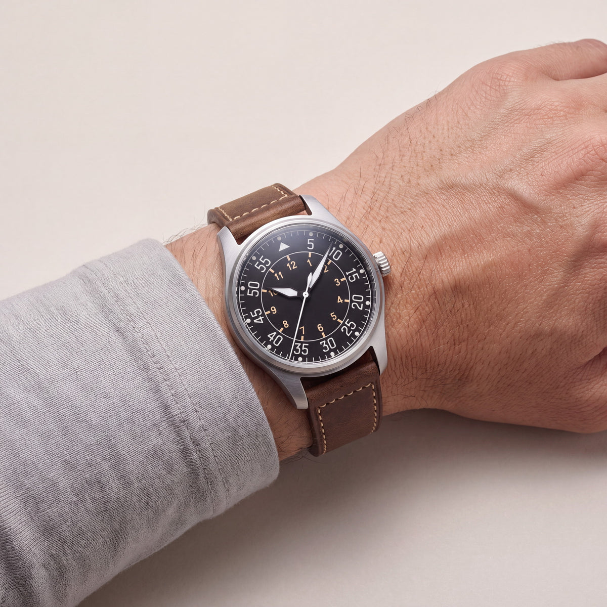 Noirmont Un — Aviateur acier porté au poignet sur bracelet cuir brun surpiqû écru — Maison Noirmont