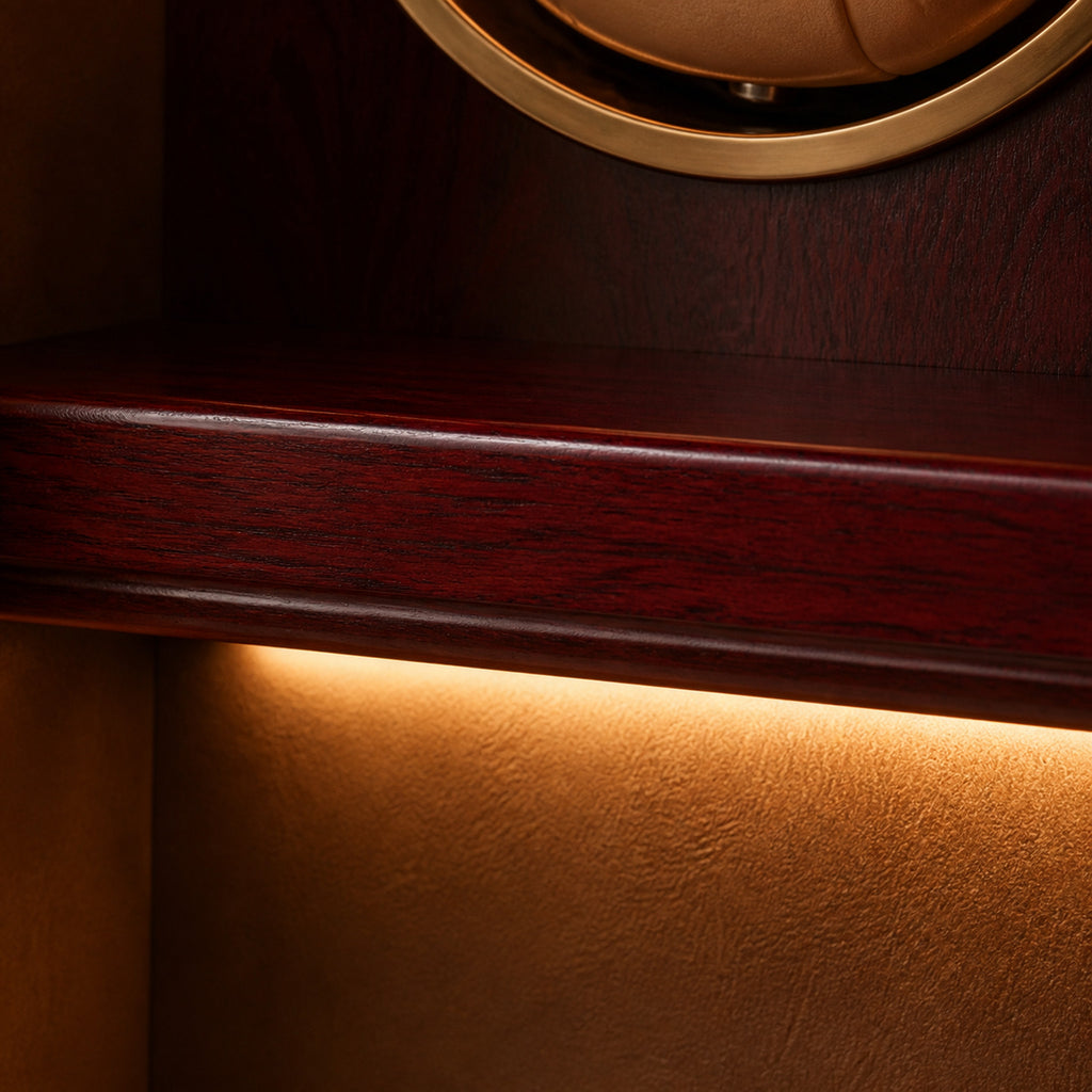 Remontoir Collection Bois LED rouge — macro du chant d'étagère en bois rouge profond, de l'entourage doré d'un logement et du halo ambré de l'éclairage LED dissimulé — Maison Noirmont